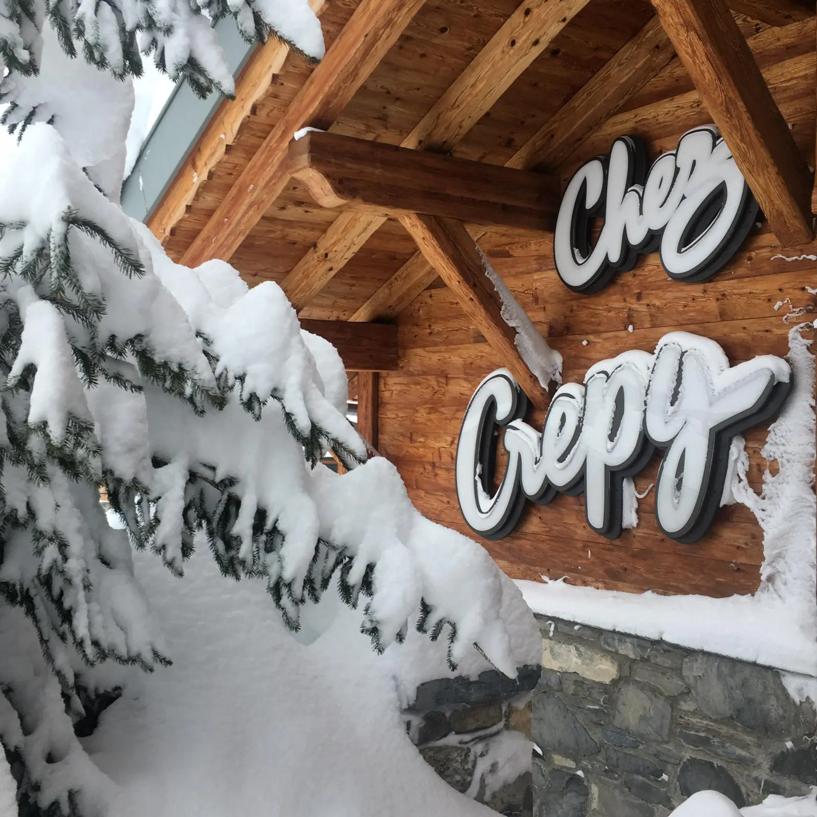 Enseigne Chez Crépy sous les branches enneigées